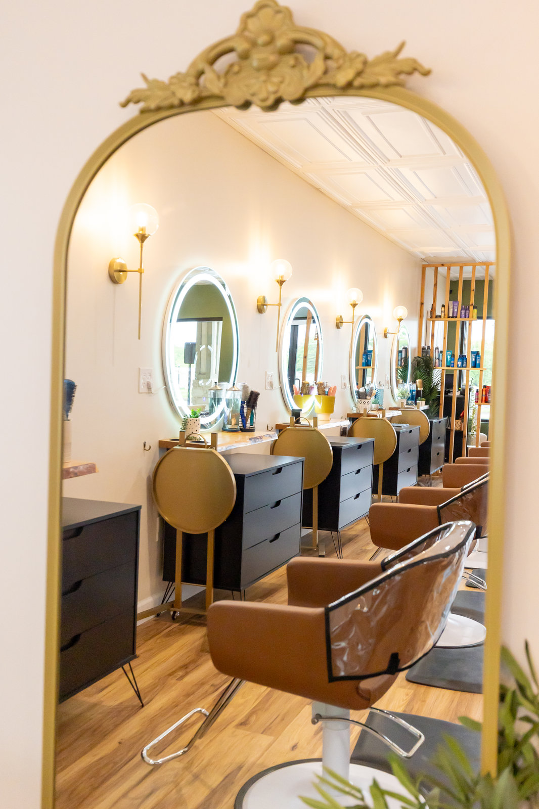 Gold styling chairs with an arched mirror at Solace Salon